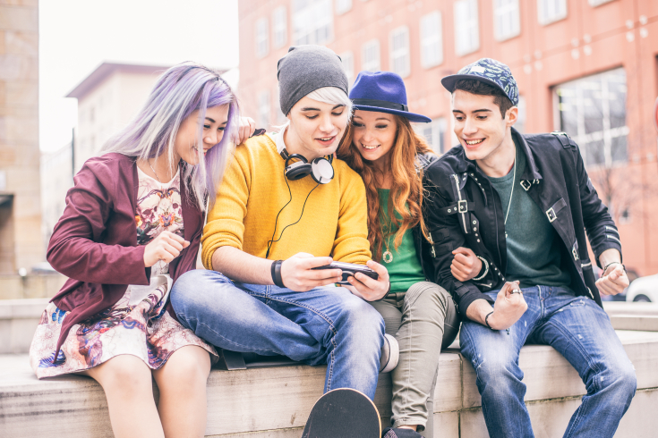 Vier Jugendliche schauen auf ein Handy