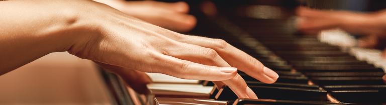 Frauenhände spielen auf einem Klavier
