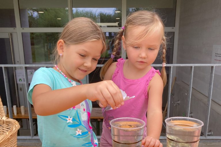 Zwei Mädchen spielen mit Steinen im Wasserbecher