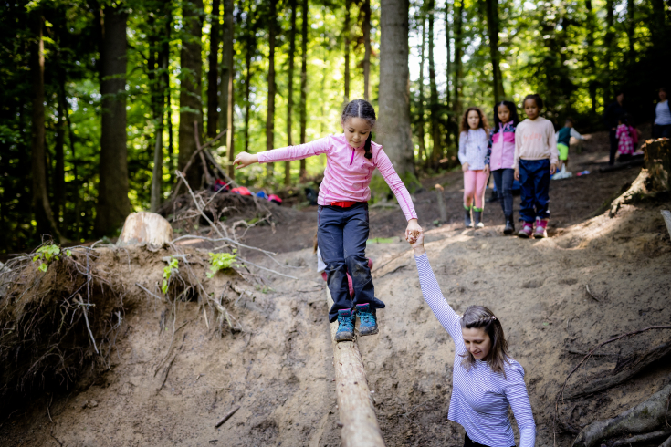 Kind die im Wald auf einem Baumstamm balanciert